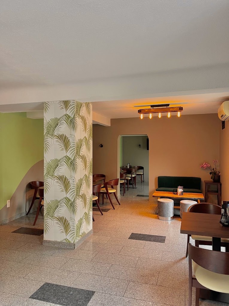 Heller Innenraum des Liberty Café Bistro mit Palmblatt-Tapete